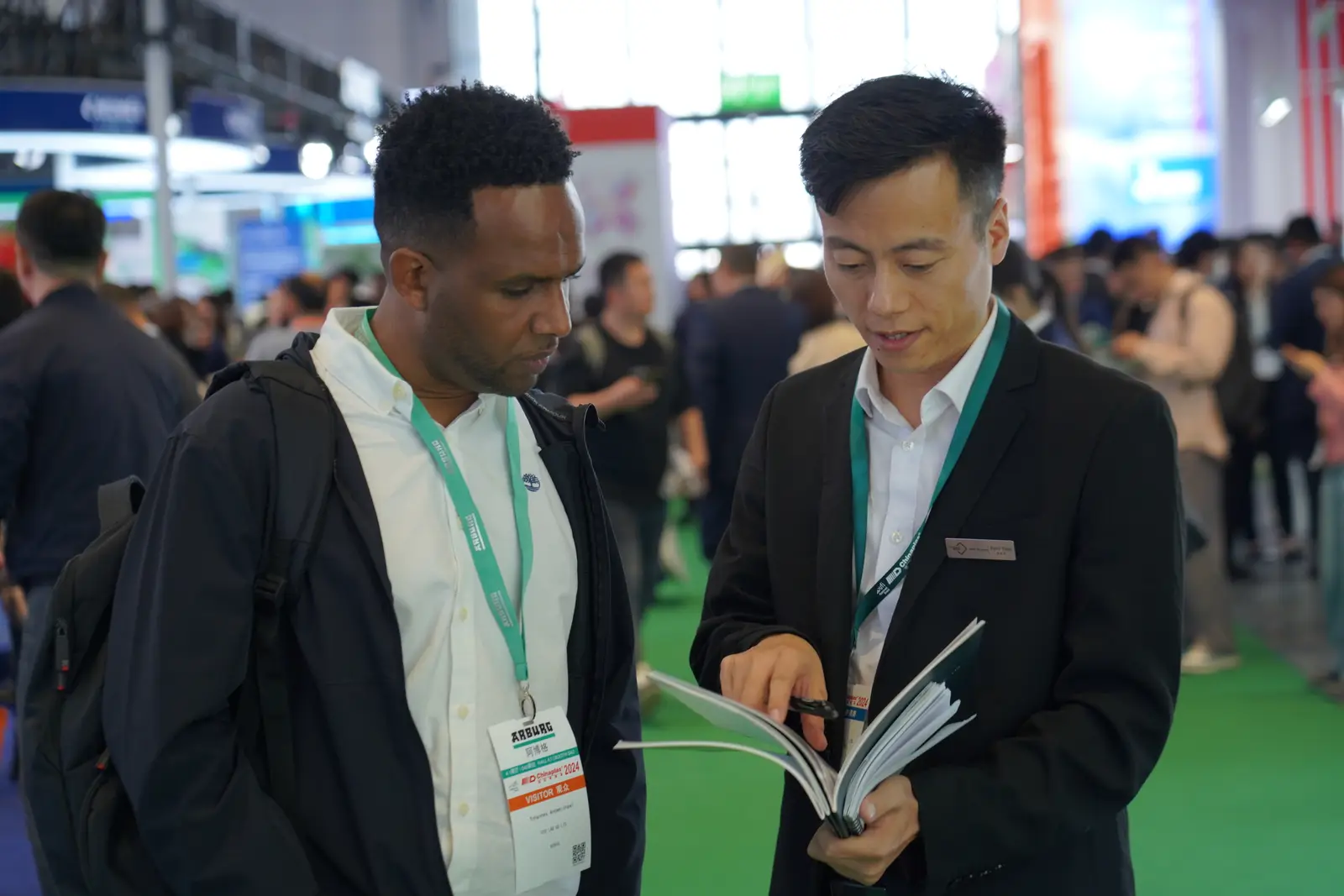 RUUIPON team reviewing silicone mold brochure with a buyer at Chinaplas exhibition